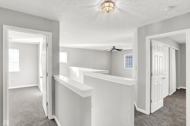 corridor featuring dark colored carpet and a textured ceiling