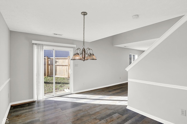 unfurnished dining area featuring an inviting chandelier and dark wood-type flooring