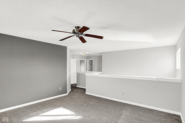 spare room featuring ceiling fan, dark carpet, and a textured ceiling