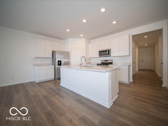 kitchen with stainless steel appliances, a center island with sink, and white cabinets