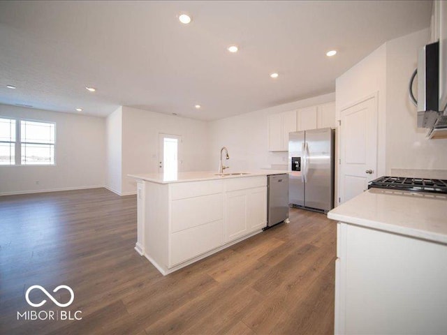 kitchen featuring dark wood-type flooring, sink, white cabinetry, appliances with stainless steel finishes, and a kitchen island with sink