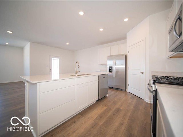 kitchen featuring dark wood-type flooring, sink, white cabinetry, a center island with sink, and stainless steel appliances