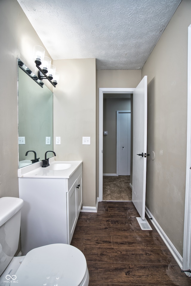 bathroom with vanity, a textured ceiling, hardwood / wood-style flooring, and toilet