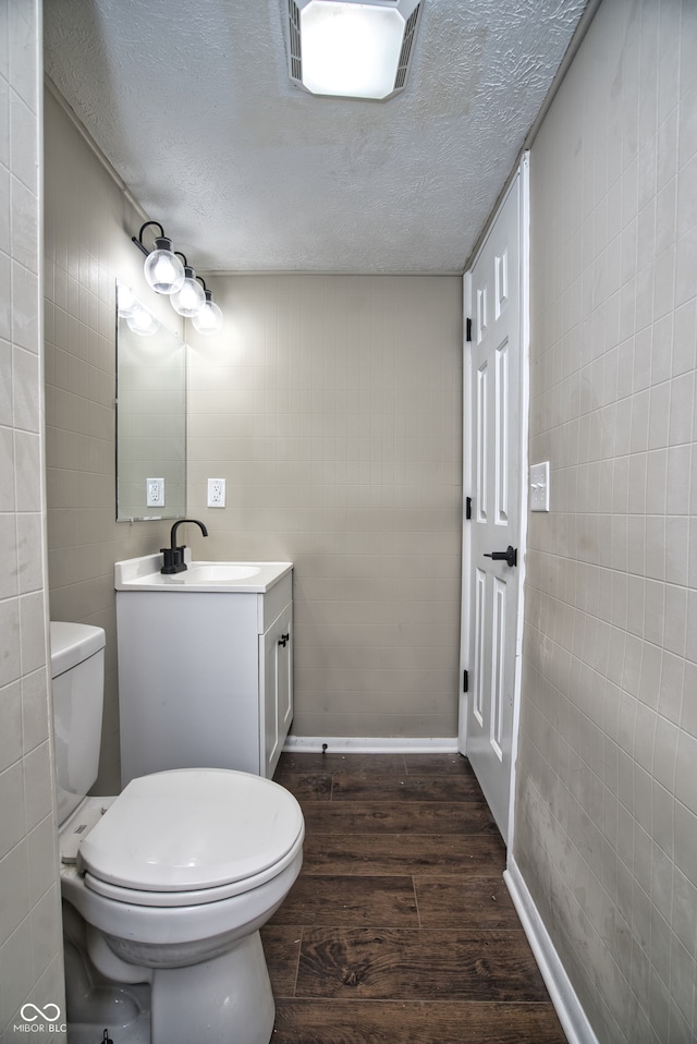 bathroom featuring vanity, a textured ceiling, hardwood / wood-style flooring, and toilet