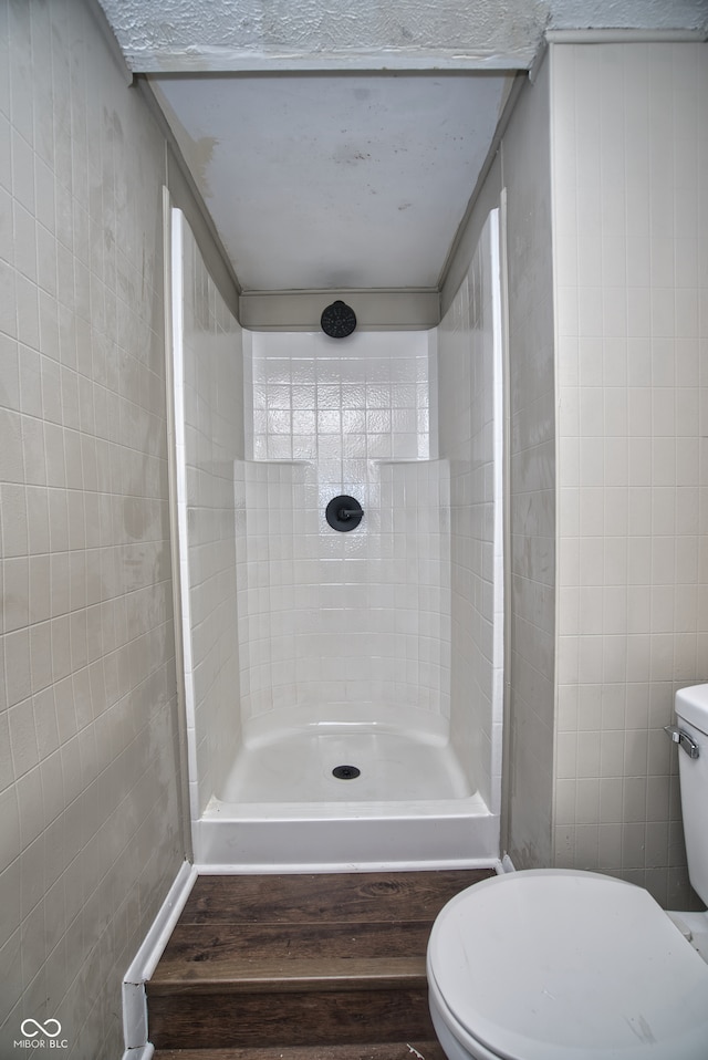 bathroom with toilet, tile walls, and walk in shower