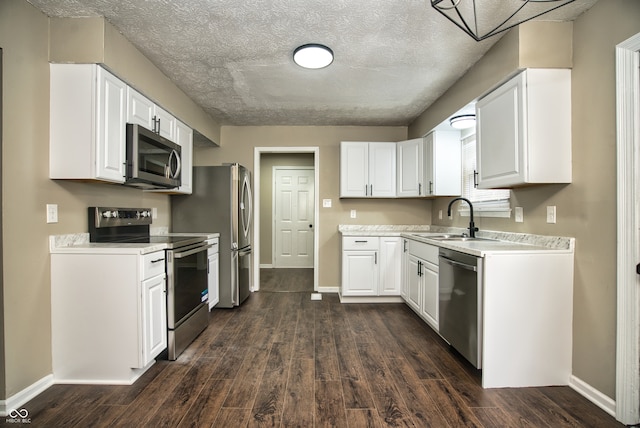 kitchen with white cabinets, sink, a textured ceiling, appliances with stainless steel finishes, and dark hardwood / wood-style flooring