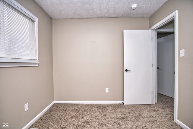 unfurnished bedroom featuring a closet, light colored carpet, and a textured ceiling