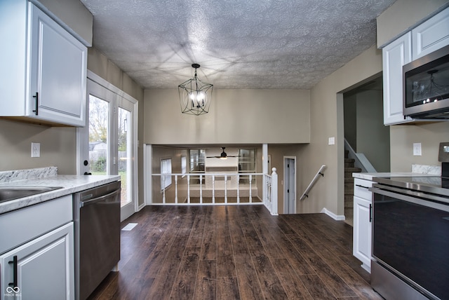 kitchen featuring white cabinetry, hanging light fixtures, stainless steel appliances, dark hardwood / wood-style flooring, and a chandelier