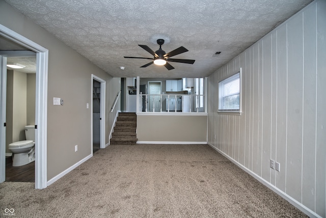 carpeted empty room featuring ceiling fan and a textured ceiling