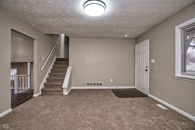 entrance foyer featuring a textured ceiling and dark carpet