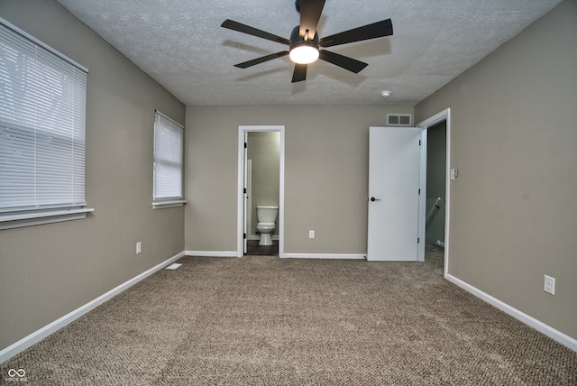 unfurnished bedroom with carpet flooring, ceiling fan, a textured ceiling, and ensuite bath