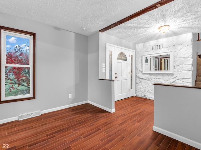 foyer entrance with a textured ceiling and dark hardwood / wood-style flooring