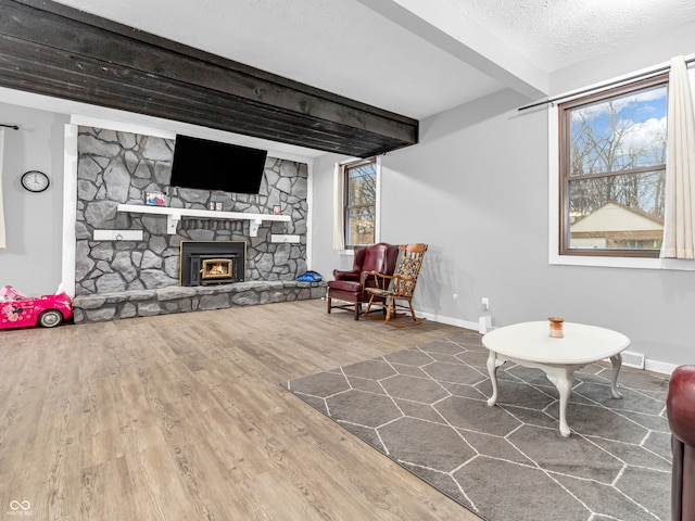 living area featuring beam ceiling, a textured ceiling, and hardwood / wood-style flooring