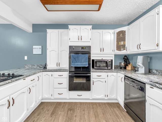 kitchen featuring white cabinets, a textured ceiling, light wood-type flooring, and black appliances