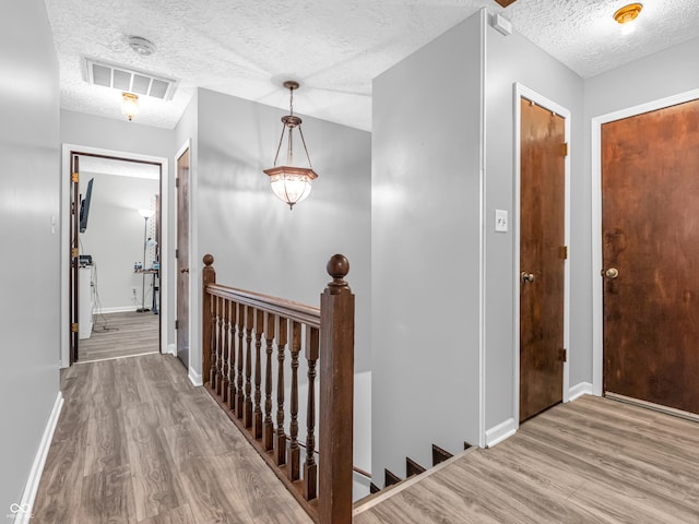 corridor with hardwood / wood-style flooring and a textured ceiling