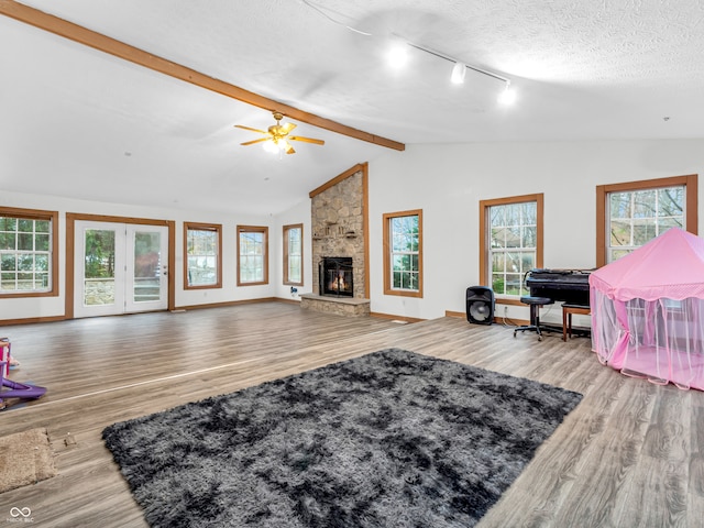 living room featuring lofted ceiling with beams, ceiling fan, light hardwood / wood-style floors, and a textured ceiling