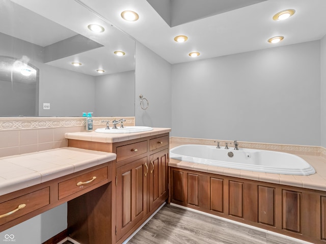 bathroom with backsplash, vanity, wood-type flooring, and a tub to relax in