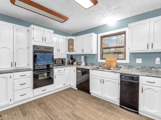 kitchen featuring black appliances, sink, light hardwood / wood-style flooring, a textured ceiling, and white cabinetry