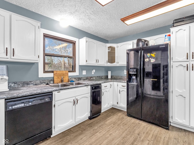 kitchen featuring sink, light hardwood / wood-style floors, a textured ceiling, white cabinets, and black appliances