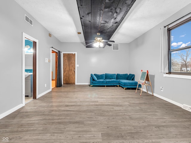 sitting room featuring ceiling fan, light hardwood / wood-style floors, and a textured ceiling