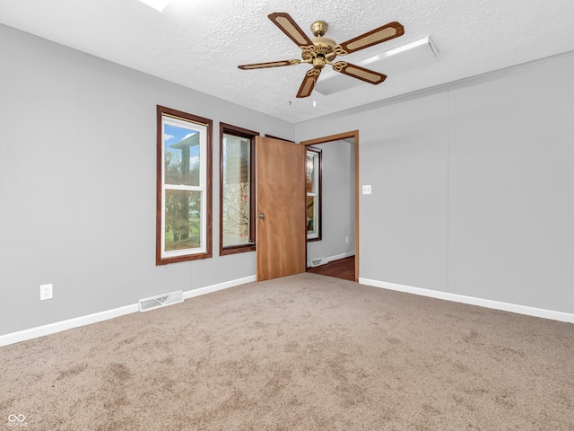 unfurnished room with ceiling fan, dark carpet, and a textured ceiling