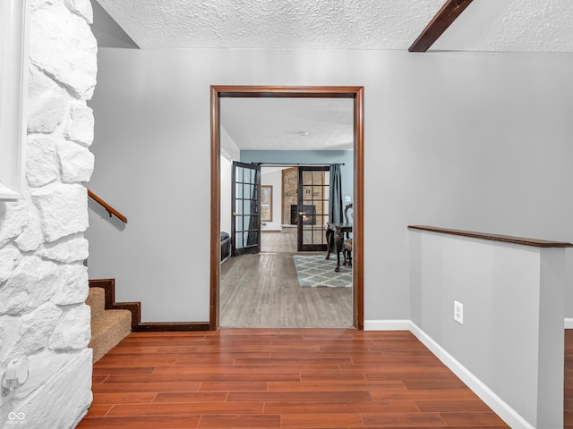 corridor featuring a textured ceiling and hardwood / wood-style flooring