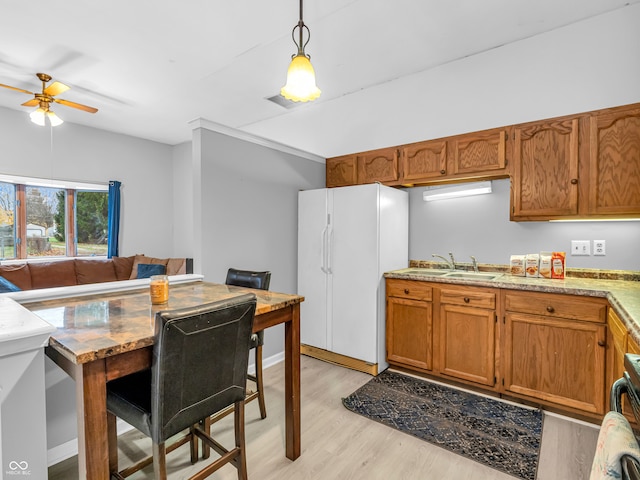 kitchen featuring white refrigerator, sink, light hardwood / wood-style flooring, ceiling fan, and decorative light fixtures