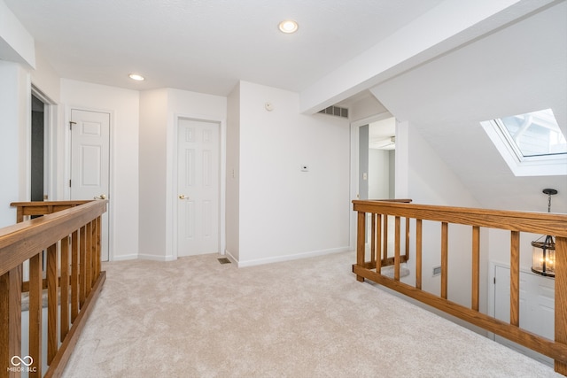 corridor with a skylight and light carpet