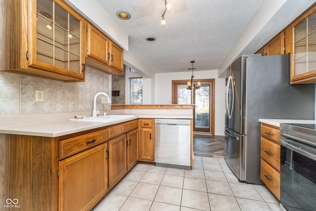 kitchen featuring light tile patterned flooring, sink, appliances with stainless steel finishes, a textured ceiling, and hanging light fixtures