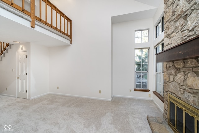 unfurnished living room with a fireplace, a high ceiling, and light carpet