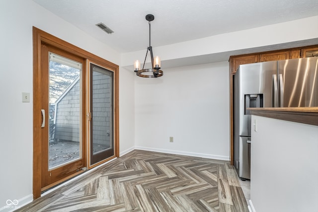 unfurnished dining area featuring a textured ceiling, dark parquet floors, and an inviting chandelier