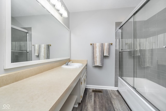 bathroom with bath / shower combo with glass door, vanity, and hardwood / wood-style floors