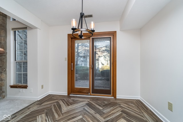 interior space featuring a textured ceiling, a notable chandelier, and dark parquet flooring