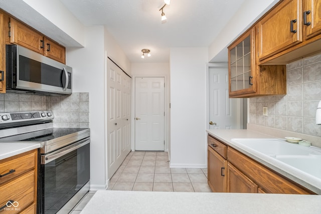 kitchen with light tile patterned floors, backsplash, and appliances with stainless steel finishes