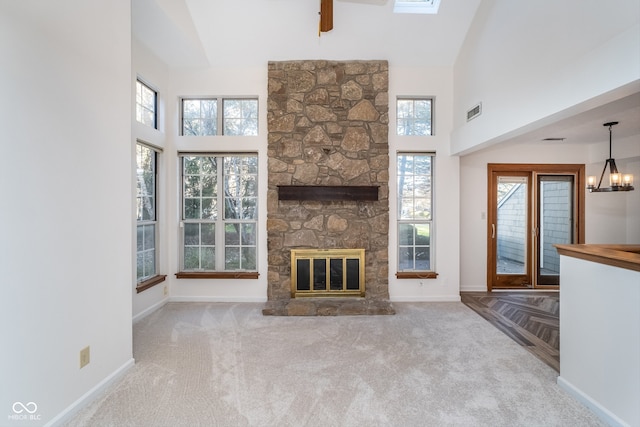 unfurnished living room featuring a stone fireplace, light carpet, and a high ceiling