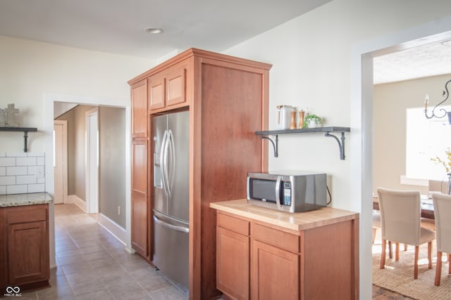 kitchen with decorative backsplash, stainless steel appliances, and light tile patterned flooring