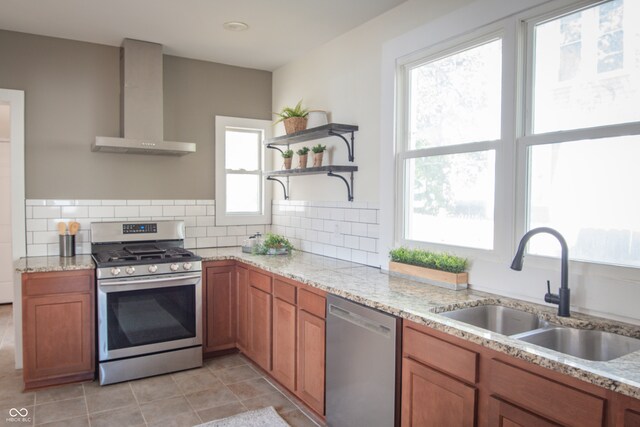 kitchen with decorative backsplash, wall chimney exhaust hood, sink, and appliances with stainless steel finishes