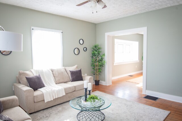 living room featuring ceiling fan, plenty of natural light, hardwood / wood-style floors, and a textured ceiling