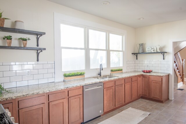 kitchen with backsplash, light stone countertops, dishwasher, and sink