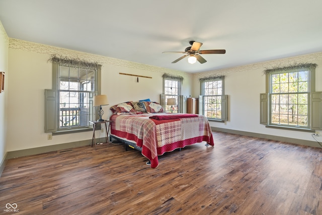 bedroom featuring multiple windows, dark wood-type flooring, and ceiling fan