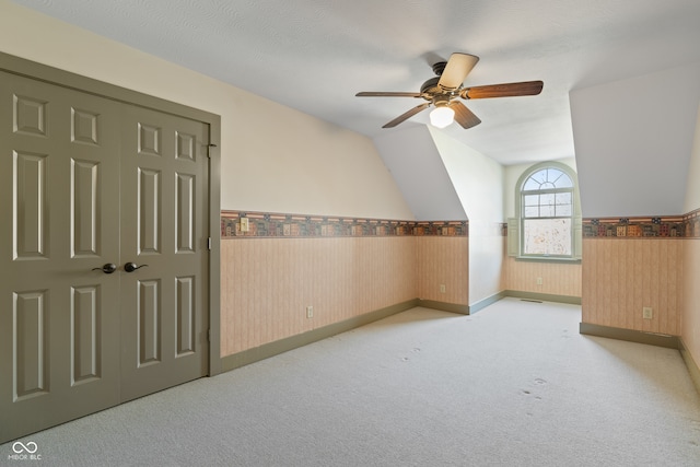 additional living space with light carpet, a textured ceiling, ceiling fan, and lofted ceiling