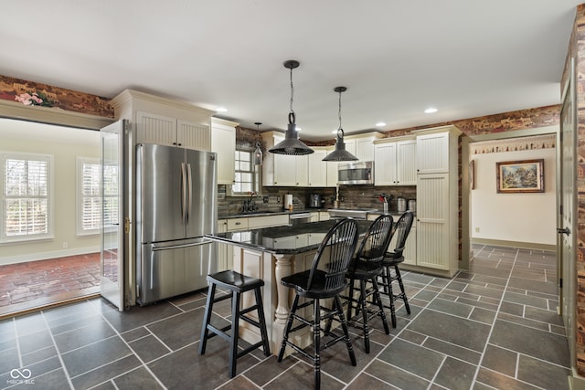 kitchen with appliances with stainless steel finishes, tasteful backsplash, sink, decorative light fixtures, and a center island