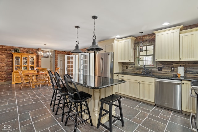 kitchen with pendant lighting, cream cabinetry, and appliances with stainless steel finishes