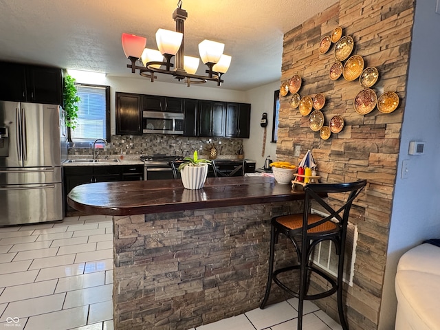 kitchen with decorative backsplash, a kitchen breakfast bar, stainless steel appliances, sink, and hanging light fixtures