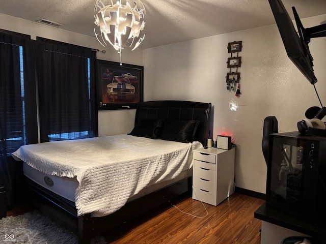 bedroom with an inviting chandelier and dark wood-type flooring