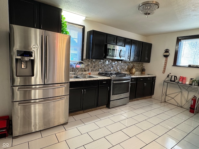 kitchen featuring tasteful backsplash, sink, stainless steel appliances, and a textured ceiling