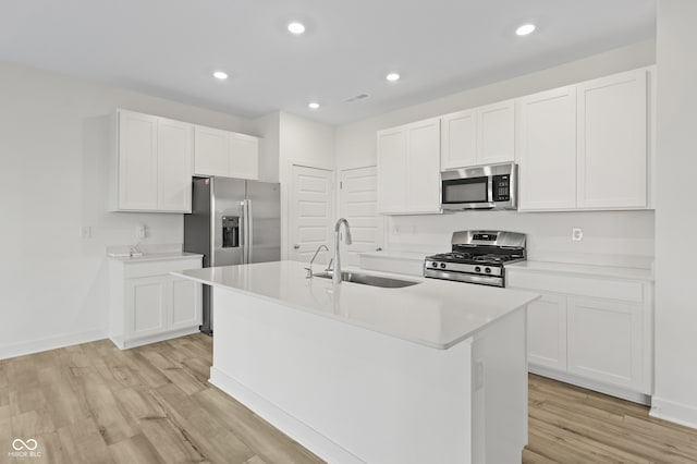 kitchen featuring white cabinets, an island with sink, stainless steel appliances, and sink