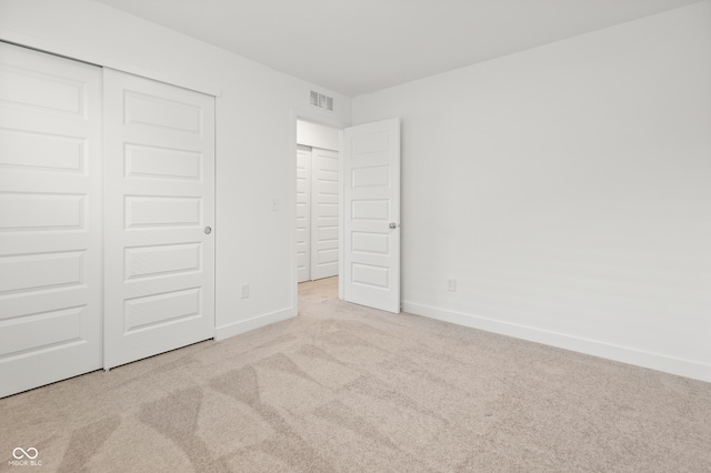 unfurnished bedroom with light colored carpet and a closet