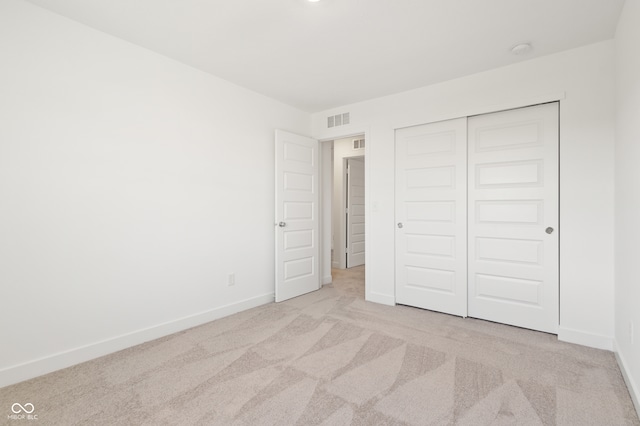 unfurnished bedroom featuring light colored carpet and a closet