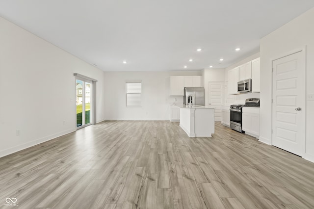 kitchen featuring a center island with sink, light hardwood / wood-style floors, white cabinets, and stainless steel appliances